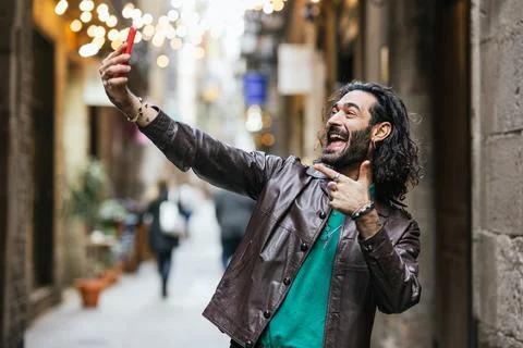 Joyful man smiling while taking selfies with a mobile phone outdoors. Foto stock