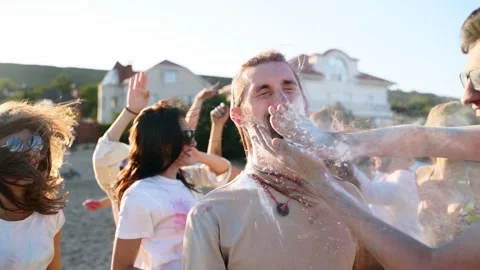 Joyful man splashes colored powder on another guy cheeks and smears his beard Stock Footage 172563746