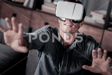 Joyful millennial guy trying on vs headset Stock Photos