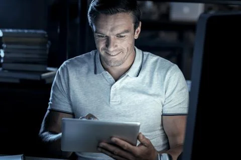 Joyful millennial man smiling while working on touchpad Stock-Fotos