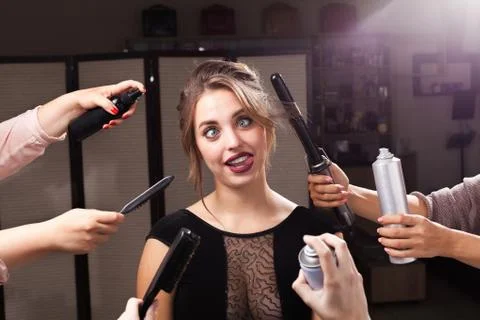 Joyful model surrounded by hands with makeup products Stock Photos