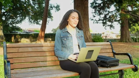 Joyful Moment of Focused Remote Work by a Young Woman in Sunny Park Environment. Stock Footage 310576821
