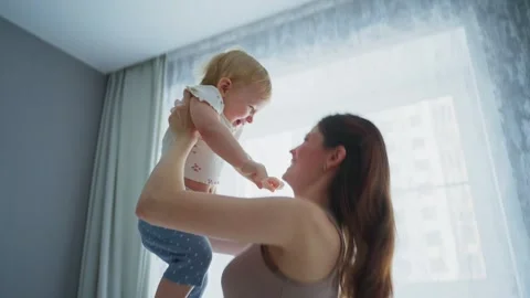 Joyful mother interacts with her smiling baby in bright room Stock Footage 307121328