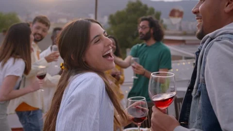 Joyful multi-ethnic couple dancing and drinking red wine celebrating rooftop Stock Footage 243083781