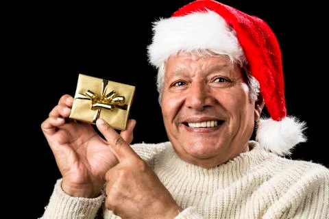 Joyful old man gesturing at wrapped golden gift Stock Photos