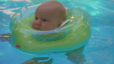 Joyful one year old boy swimming with mother in pool, using inflatable neck Stock Footage 336566762