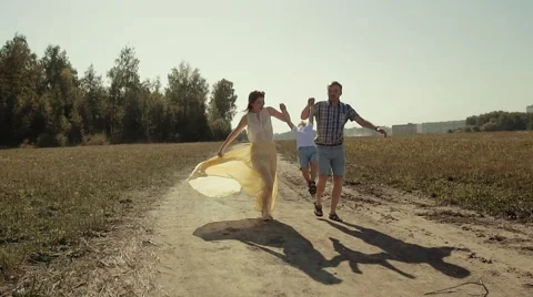 Joyful parents lift their son up while running along countryside road Stock Footage