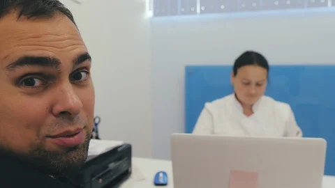 Joyful patient is talking to smb while doctoris typing onher laptop. Stock Footage 124468344