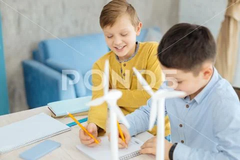 Joyful pre-teen boys drawing sketches of wind turbines together Stock Photos
