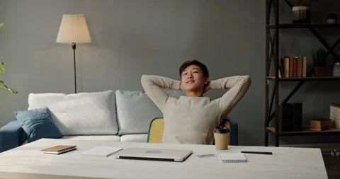 Joyful remote worker laid back on his chair. Positive asian male student happy Stock Footage 127305172