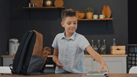 Joyful schoolboy prepares backpack for school. Back to School. Stock Footage 92498801