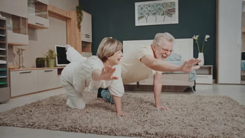 Joyful senior couple practicing yoga and sharing a tender moment at home. Stock-Footage 327538488