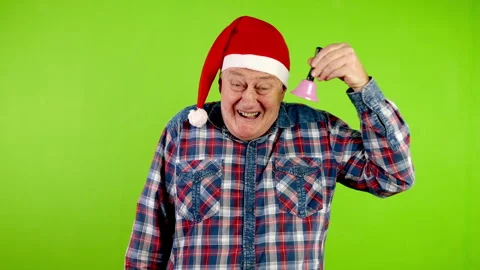 Joyful senior man in Santa hat rings Christmas jingle bell and laughs. Stock Footage 253745737