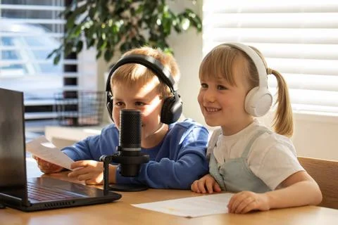 Joyful siblings sharing a laugh while recording a podcast at home. Blogging 스톡 사진