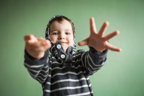 Joyful smiling boy posing with arms stretched out in welcome gesture. Stock Photos