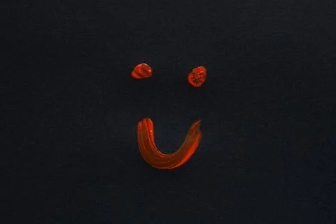 A joyful smiling face is drawn with red paint on a black background as a sy.. Stock Photos
