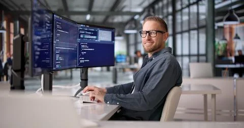 Joyful Software Developer Coding With Several Screens In Office Setting Foto stock