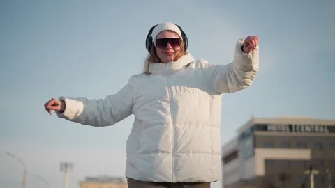 Joyful Student Dancing in Sunlight Wearing Winter Jacket and Headphones Video stock 307457499