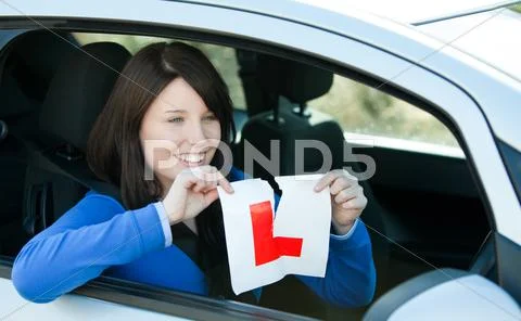 Joyful teen girl sitting in her car tearing a L-sign Stock Photos