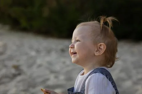 Joyful toddler with a tiny ponytail laughing outdoors on a sunny day Stock Photos