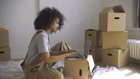 Joyful Woman Typing on Computer Amidst Moving Carton Boxes Stock Footage 313351691