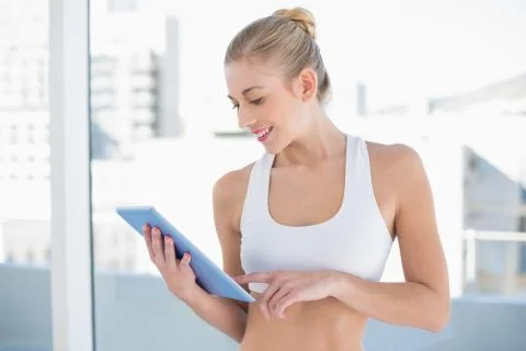 Joyful young blonde model using a tablet pc Stock Photos
