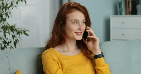 Joyful young Caucasian red-haired woman talking on cellphone and smiling and Stock Footage 130159743