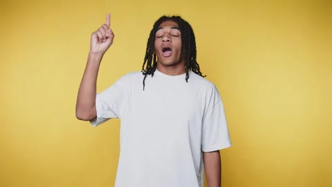 Joyful young man with braids, hand raised as if singing, showcasing a vibra.. Stock Footage 313280080