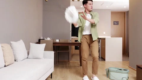 Joyful young man guy listening music and washing floor use mop dancing singing Stock Footage 336172726