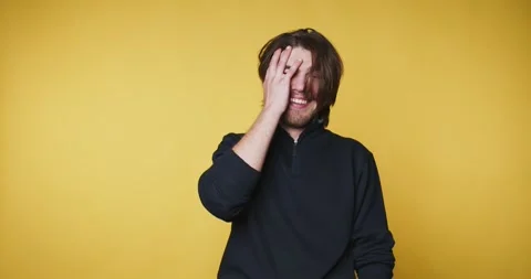 Joyful young man playfully covers his face with one hand, showcasing happin.. Stock Footage 314336958