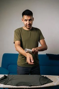 Joyful young man using sticky lint roller to efficiently remove hair and fluff Stock Photos