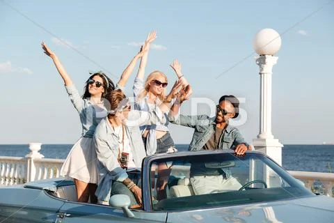 Joyful young people giving high five and driving cabriolet Stock Photos