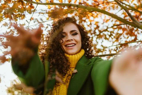 Joyfully pulls her hands forward and smiles beautiful curly brunette against the Stock Photos