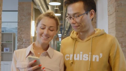 Joyous Colleagues Chatting and Using Smartphone while Walking through Corridor Stock-Footage 126135177