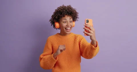 Joyous friendly looking curly ethnic girl waves palm at smartphone camera says Stock Footage 144922692