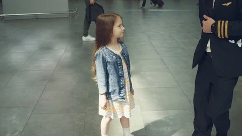 Joyous smiling pilot presenting toy pink plane to a little cute girl in terminal Stock Footage 108868577
