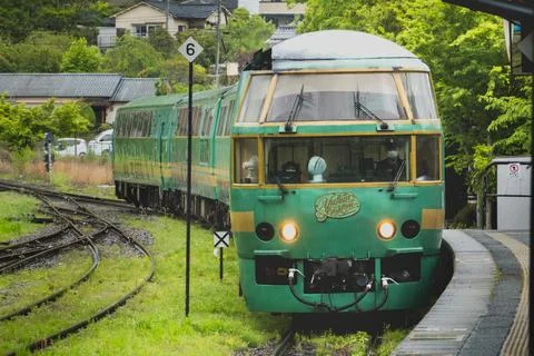 JR Kyushu's designed train Yufuin no mori heading to park among green scene.. Stock Photos