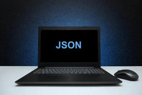 JSON text on laptop screen on textured black background with blue light. Stock Photos