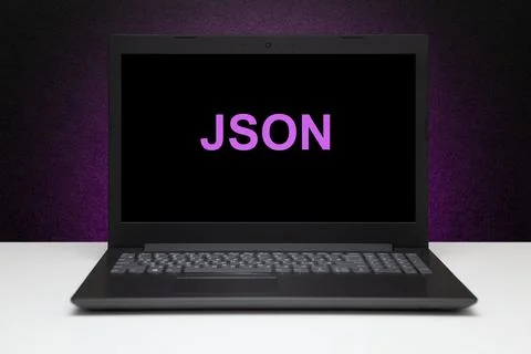 JSON text on laptop screen on textured black background with purple light. Stock Photos