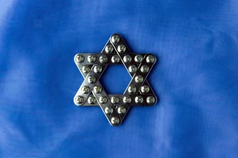 Judaism: shiny star of David, built with meccano, lies on blue fabric, top vi Stock Photos
