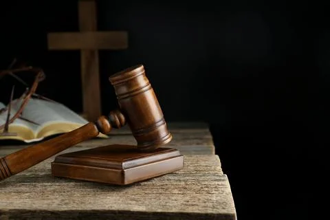 Judge gavel, bible, cross and crown of thorns on wooden table against black.. Stock Photos