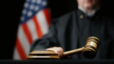 Judge hammering with wooden gavel American flag in United States court room Stock Footage