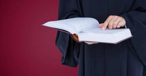 Judge mid section with open book against maroon background Photos