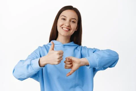 Judgement. Smiling girl shows like dislike, thumbs up and thumbs down, two Stock Photos