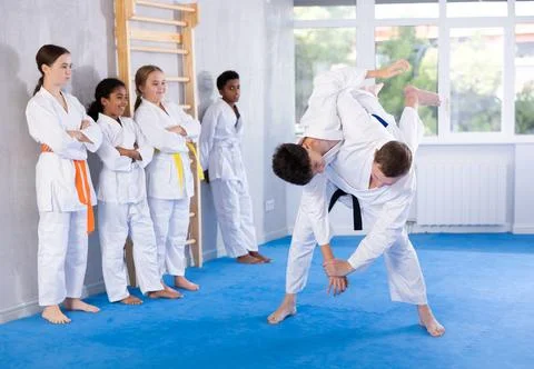 Judo coach shows fighting techniques in sparring with a boy for group of young Stock Photos