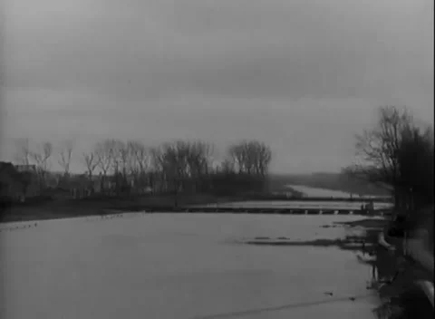 JUELICH, GERMANY - 1945: Bare level shoreline - Flood water meets a low span Stock Footage 344599423