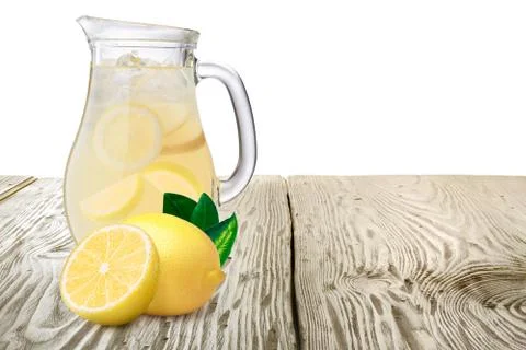 Jug or pitcher of lemonade with lemons on foreground standin on wooden table Stock Photos