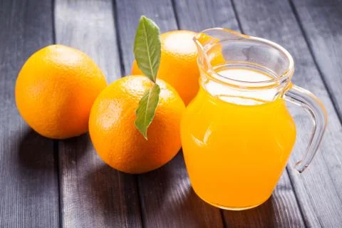 Jug of orange juice on the table, rustic still life Stock Photos