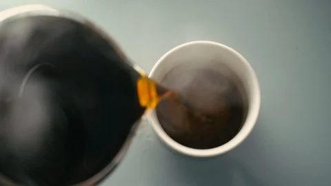 A jug pours steaming coffee into a cup Stock Footage 100054718