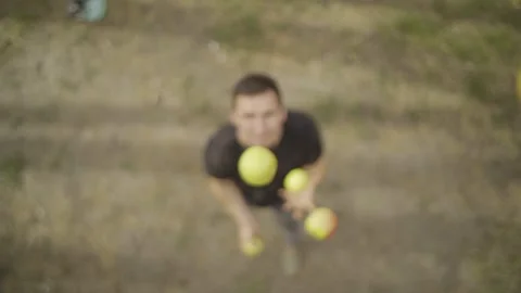 Juggler skillfully tossing vibrant green apples into the air, showcasing dynamic Vidéo 332847404
